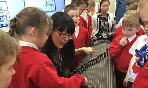 Children in a music workshop looking at a stringed instrument